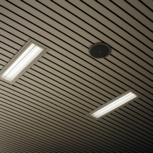 KU型黑縫片長條鋁板天花板安裝實景，搭配嵌入式照明與圓形揚聲器